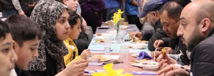 Exmouth Community sat at tables sharing food and talking with daffodils on the table 